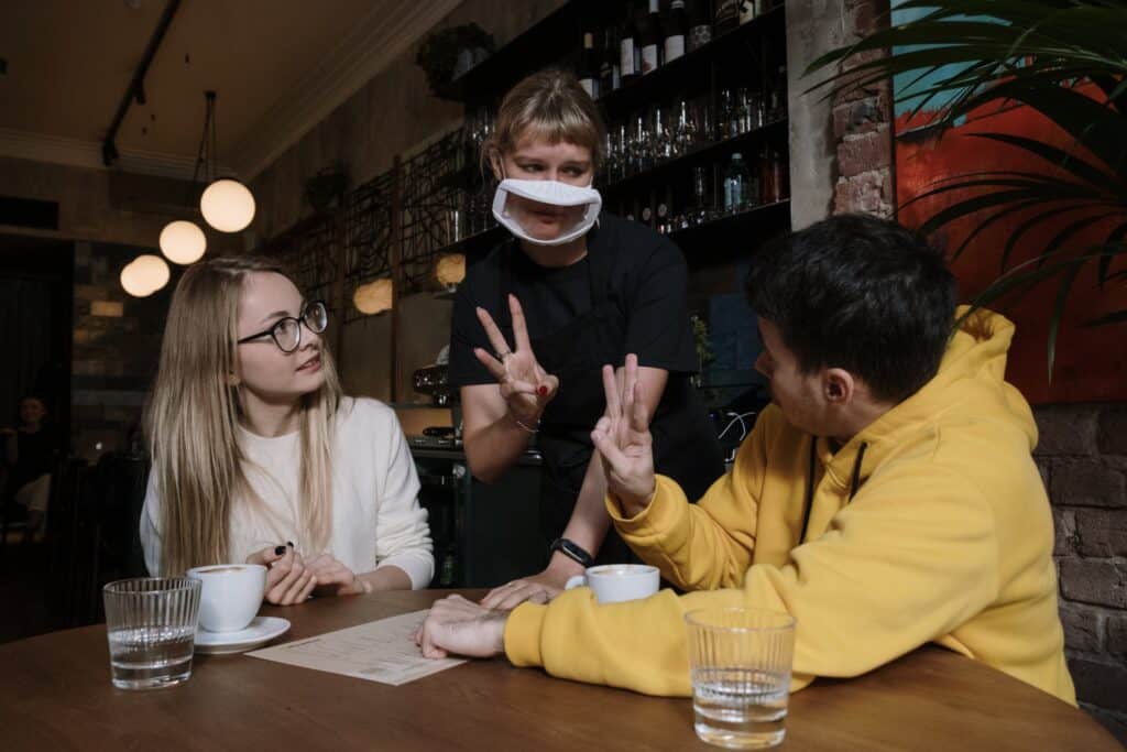 A young couple communicate via sign language to their server at a cafe.