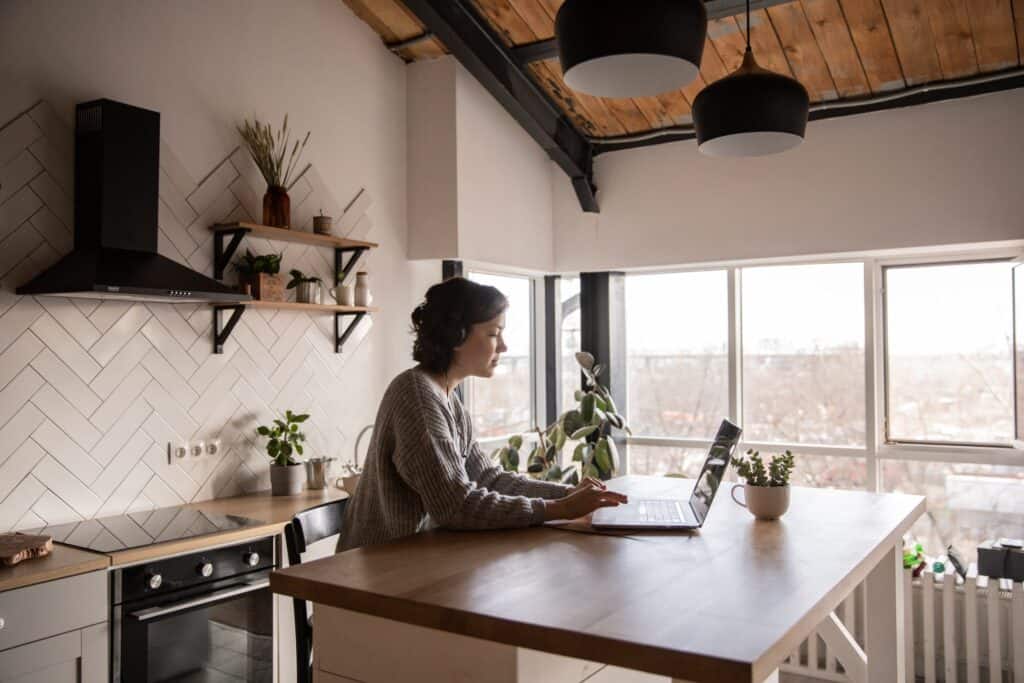 Woman on a kitchen island working on her computer. 