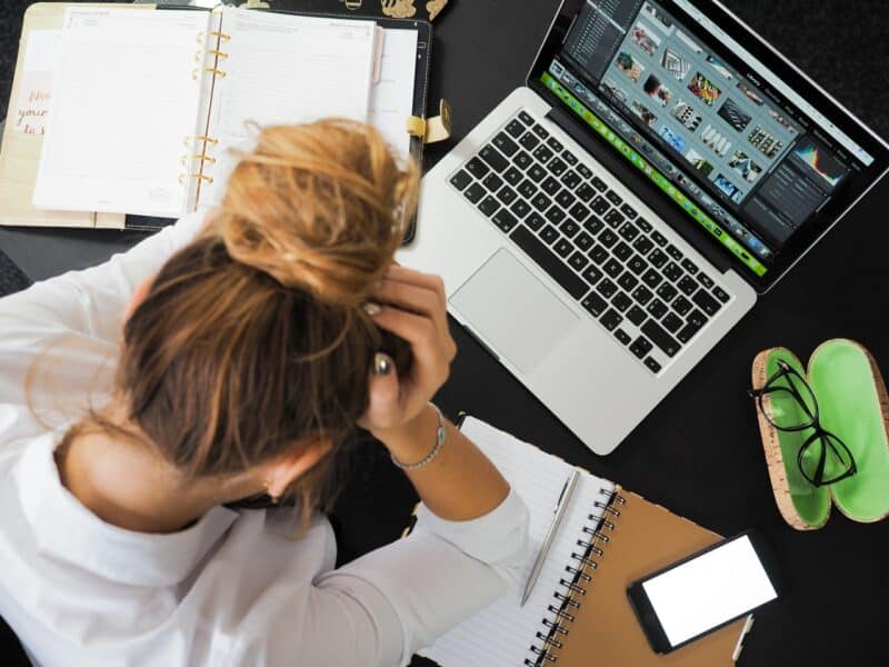 Stressed woman with notebooks and laptop around her