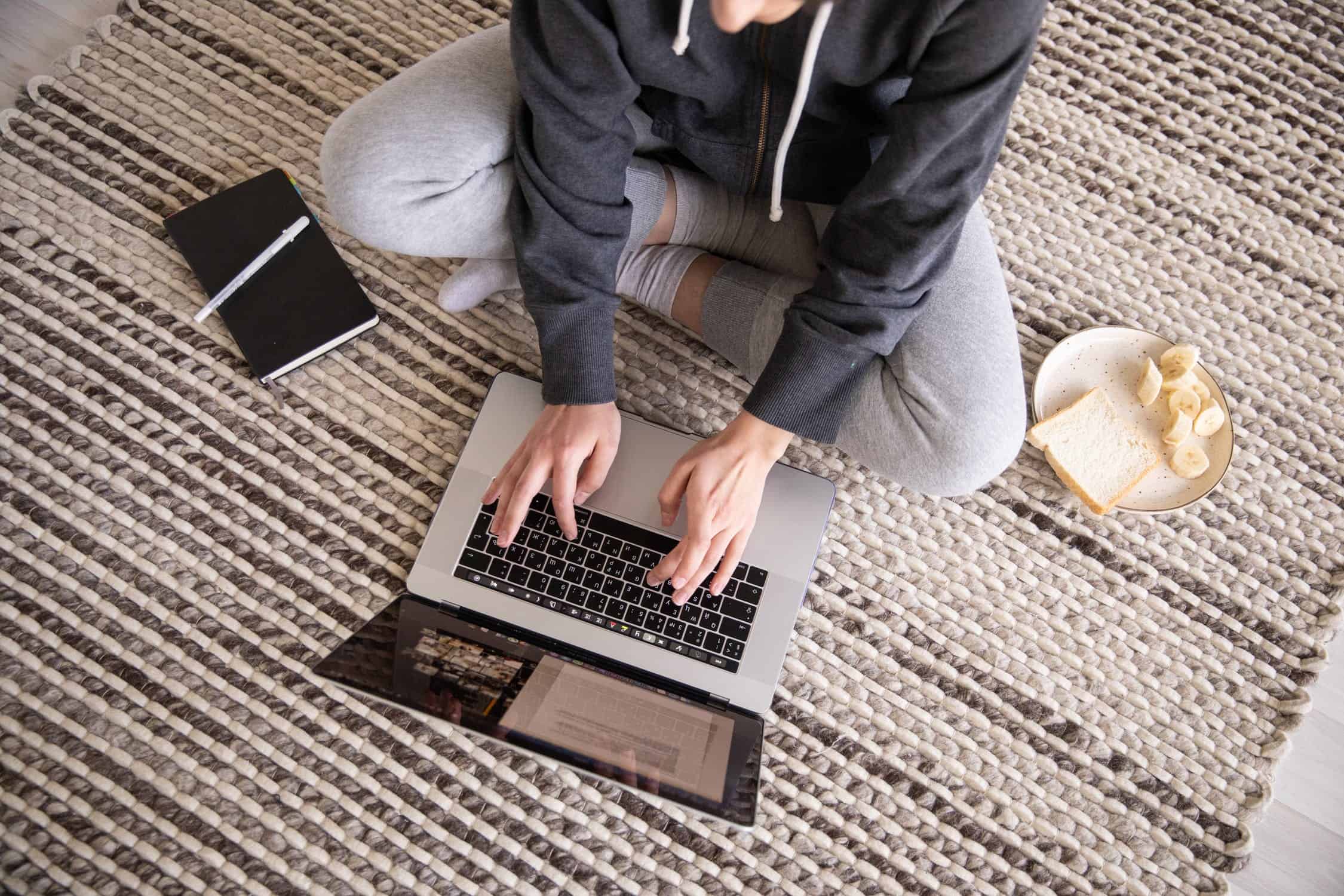 Person sittng on the floor working on a computer.