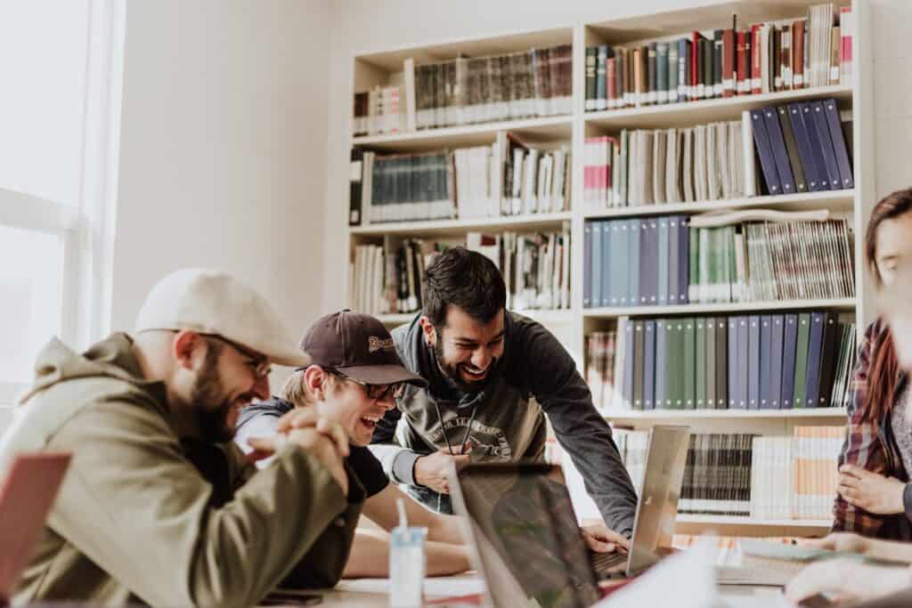 Three guys laughing and staring at a computer