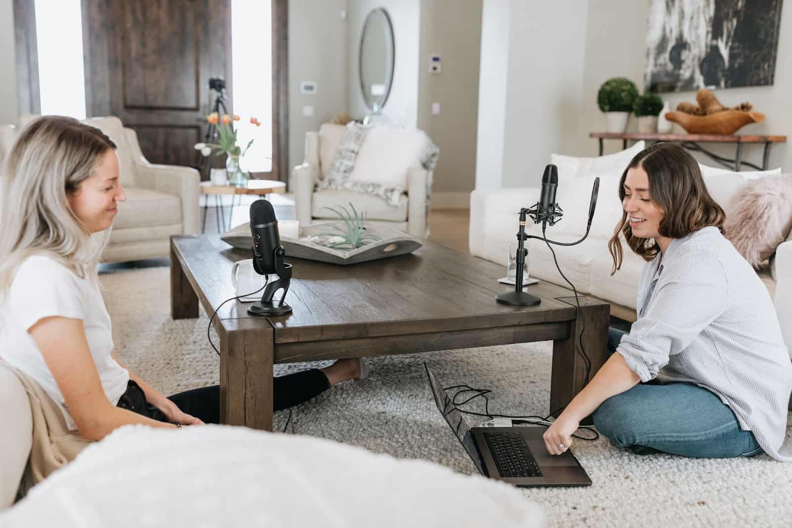 Two girls sitting on a rug recording a podcast