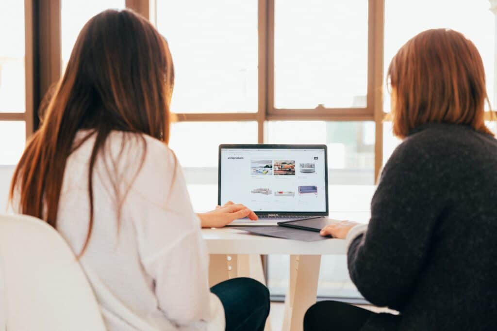 Two young, working women collaborating over work on computer