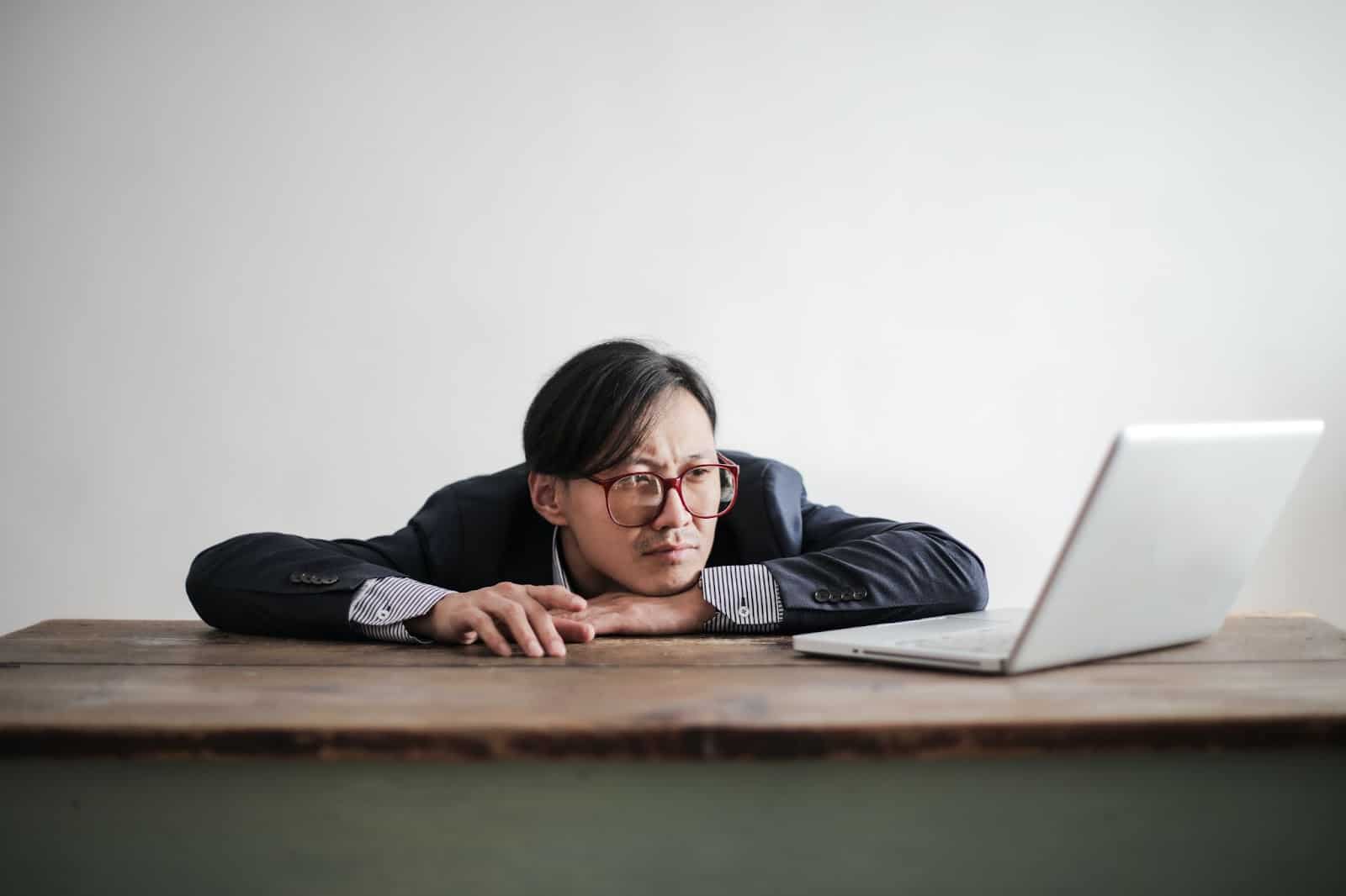 Man staring at laptop disheartened.