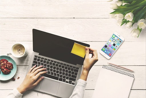 Woman sticks post it note on laptop computer