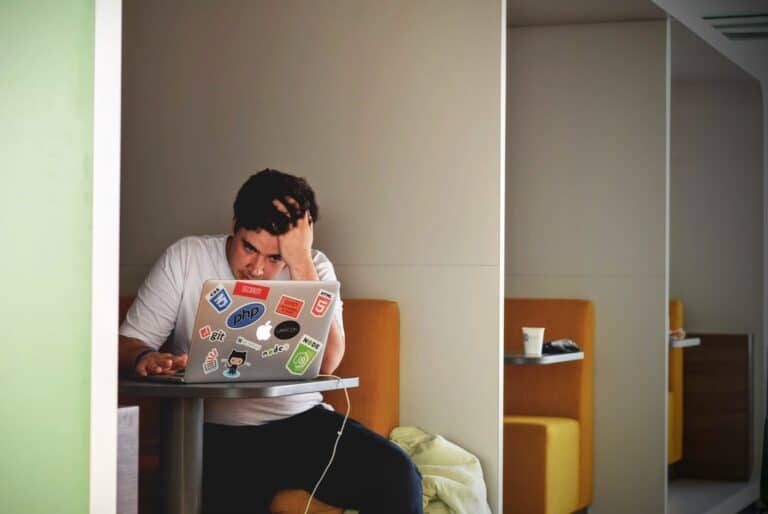 A frustrated man operating a laptop